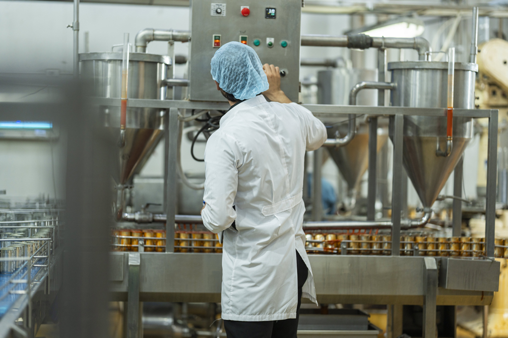Medewerker in beschermende kleding bij een productielijn in de voedingsindustrie
